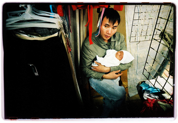 An Asian man holds an infant in his arms