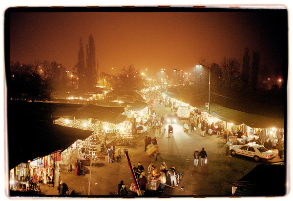 The local market at night lit up with yellow lights, going out into the distance