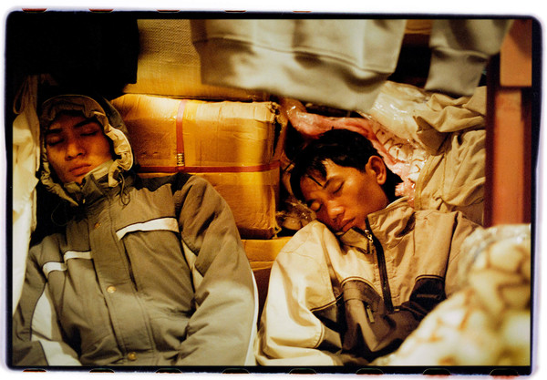 Two Asian guys sleeping in a warehouse.
