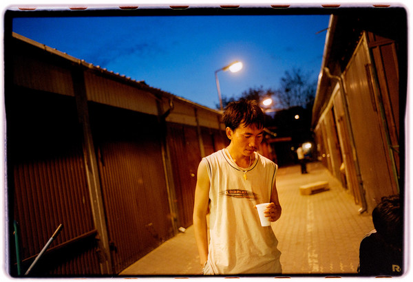 Facet stojący nocą na ulicy z kubkiem kawy.