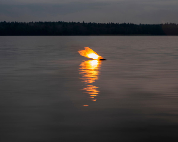 A lake with something burning in the middle of it.