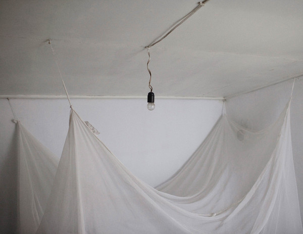 A picture of a pale shade, with a light bulb on the ceiling and white sheets stretched out underneath like a parachute